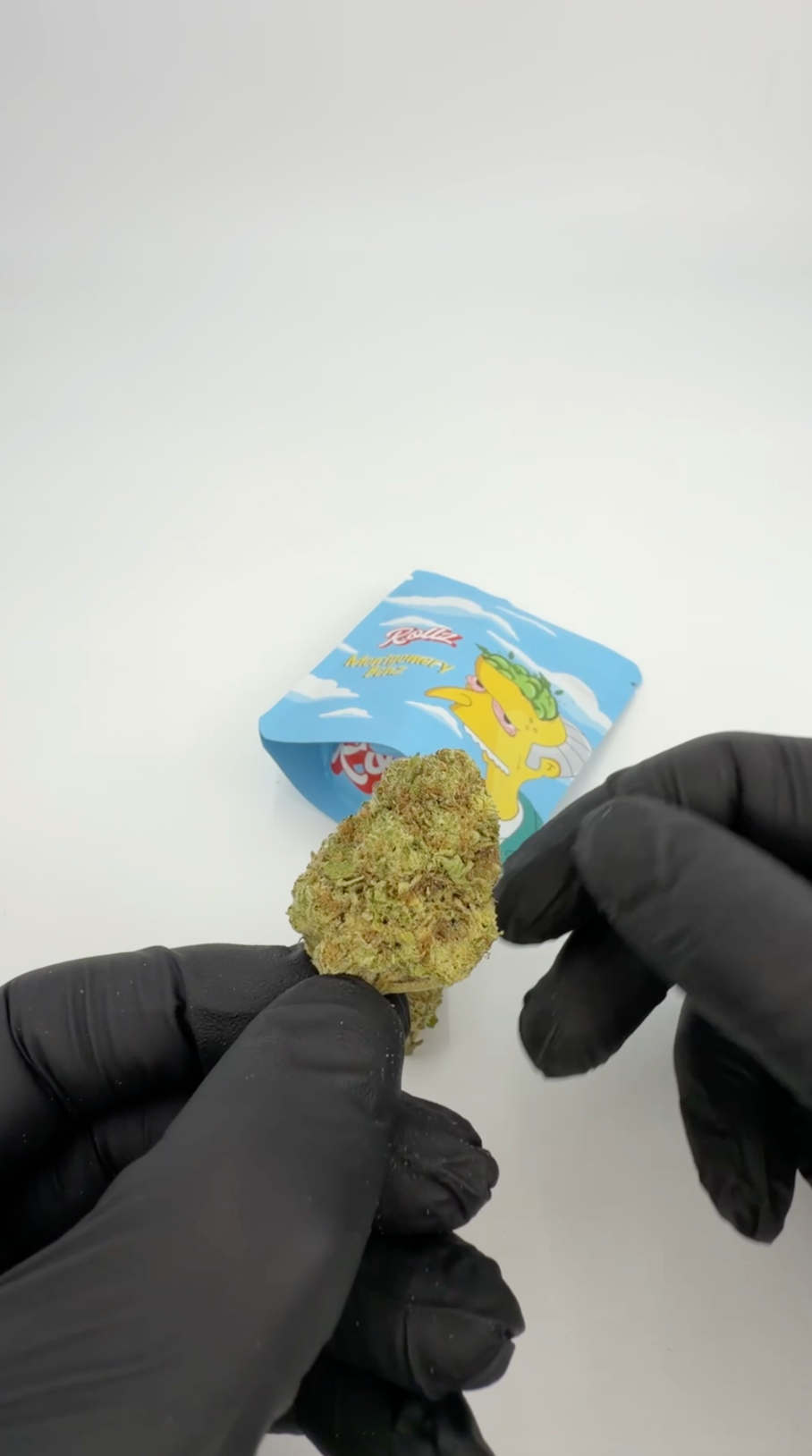 Rollz Montgomery Benz THCA indoor flower pouch with cartoon design and dried cannabis flower in front on a white background
